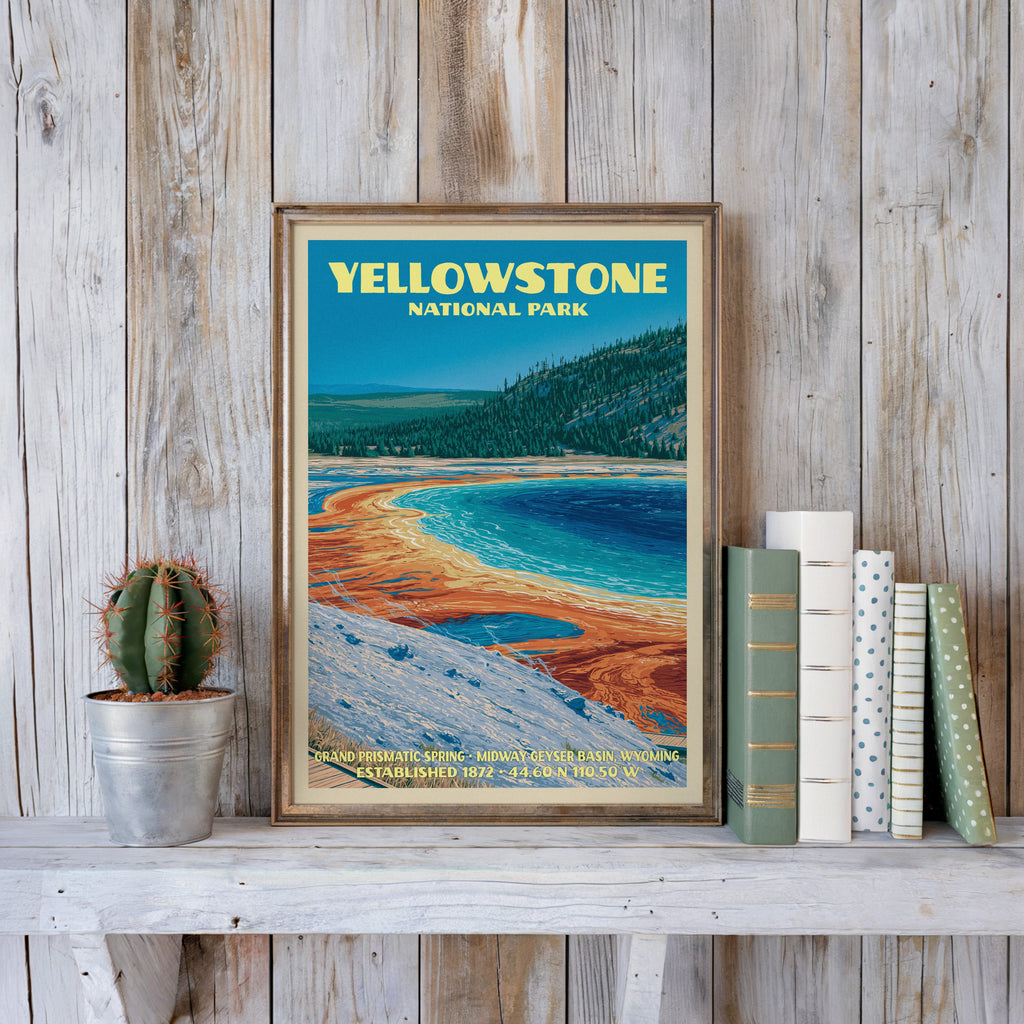 Yellowstone vintage poster in a slim gold frame on a whitewashed plank wall beside a cactus and pastel books