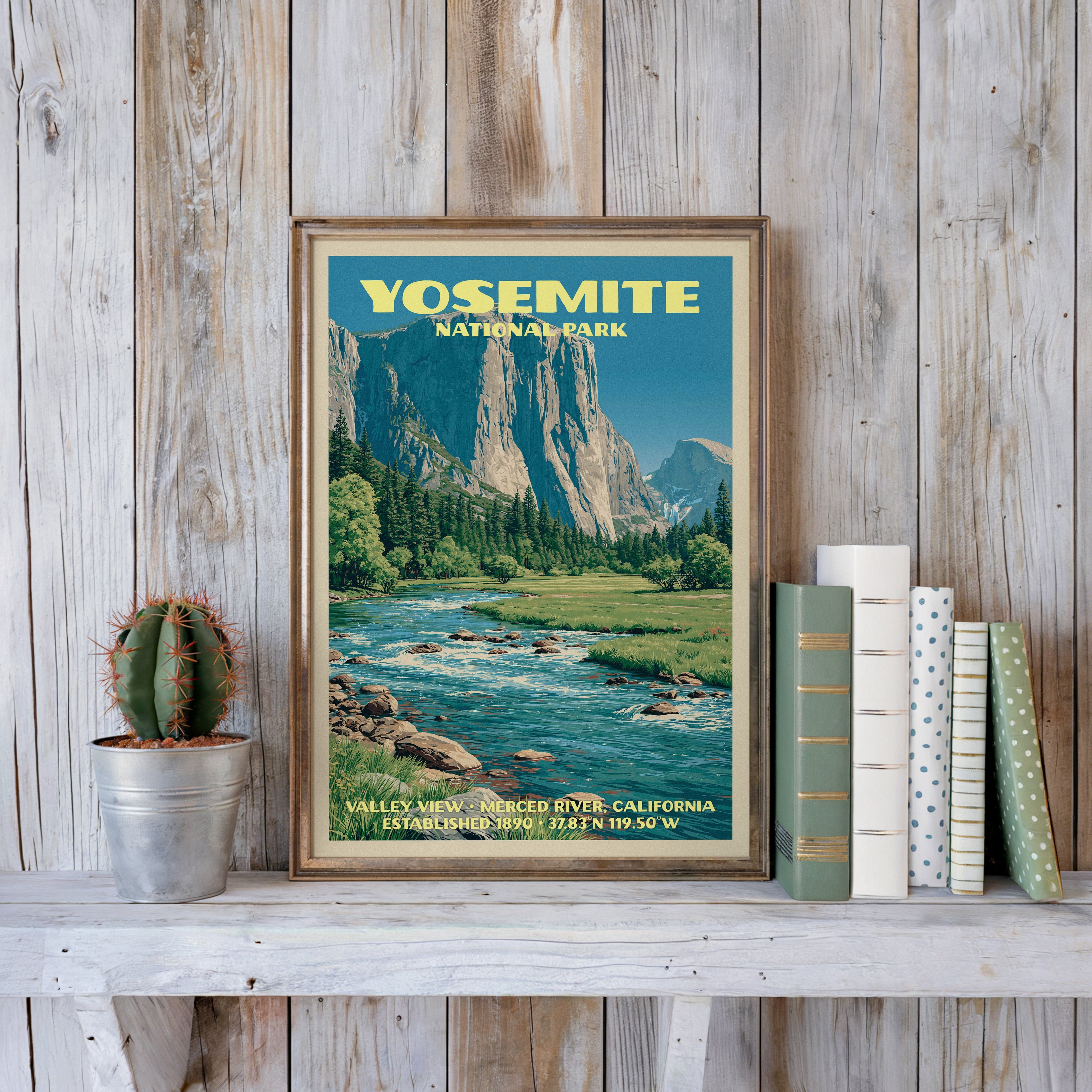 Yosemite vintage poster in a slim gold frame on a whitewashed plank wall beside a cactus and pastel books