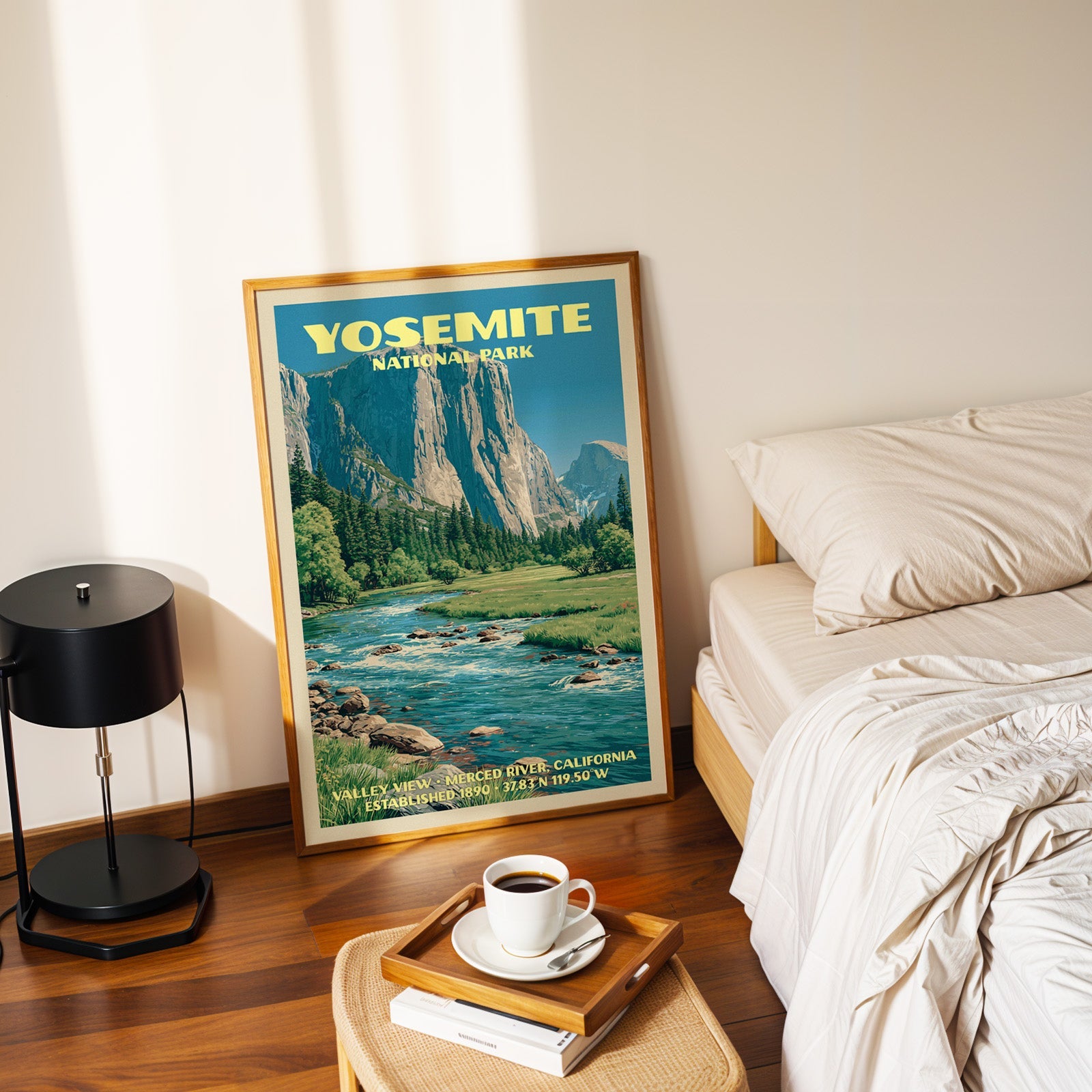 Valley View Yosemite poster in a gold frame on the bedroom floor beside a made bed and a black table lamp