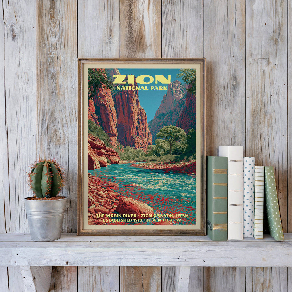 Zion vintage poster in a slim gold frame on a whitewashed plank wall beside a cactus and pastel books