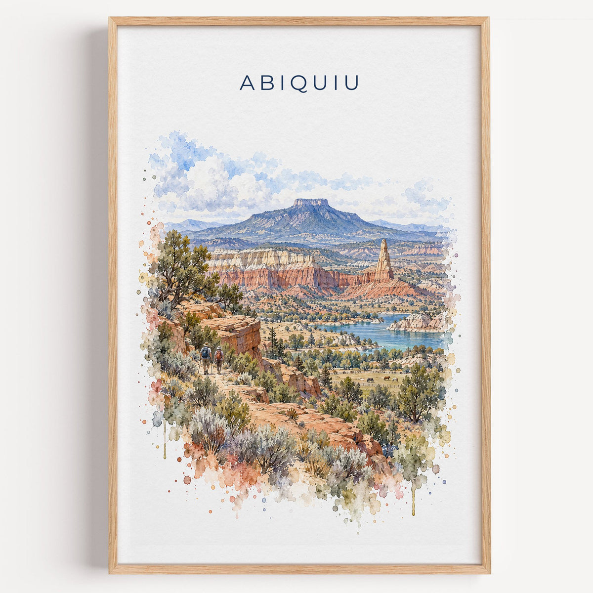 Abiquiu, New Mexico watercolor print in a light oak frame on a plain white wall