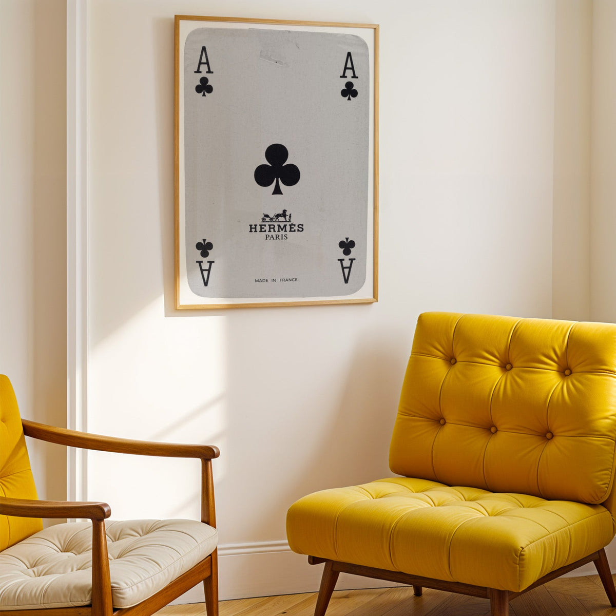 Worn vintage ace of clubs playing card print shown in a gold frame above a mustard yellow tufted armchair