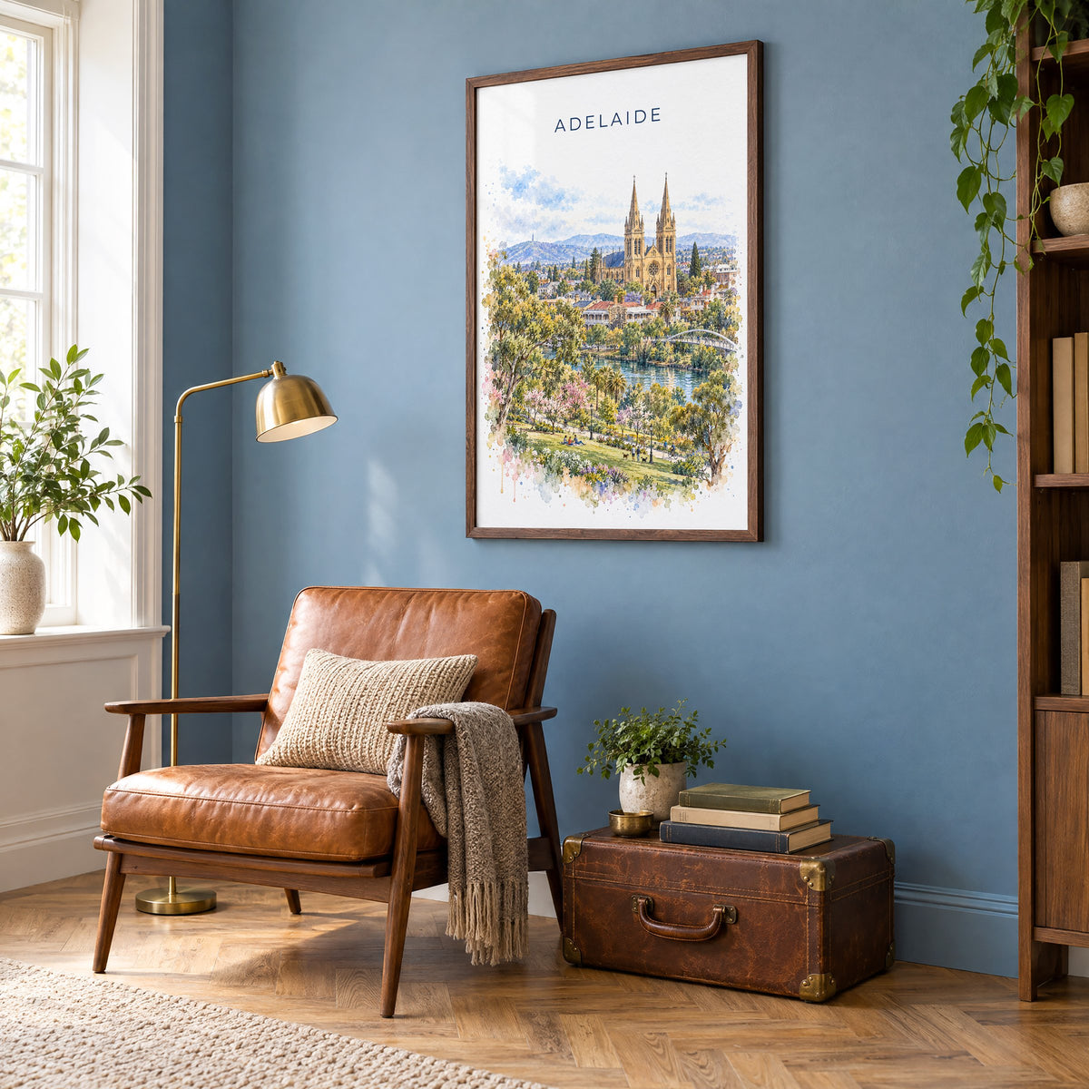 Adelaide watercolor print in a walnut frame on a blue wall above a leather armchair in a reading nook