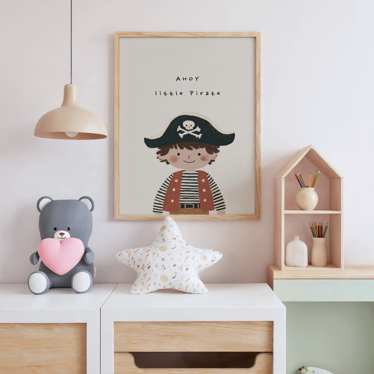 Ahoy little pirate boy nursery print in an oak frame above a white dresser with a star pillow and house shelf