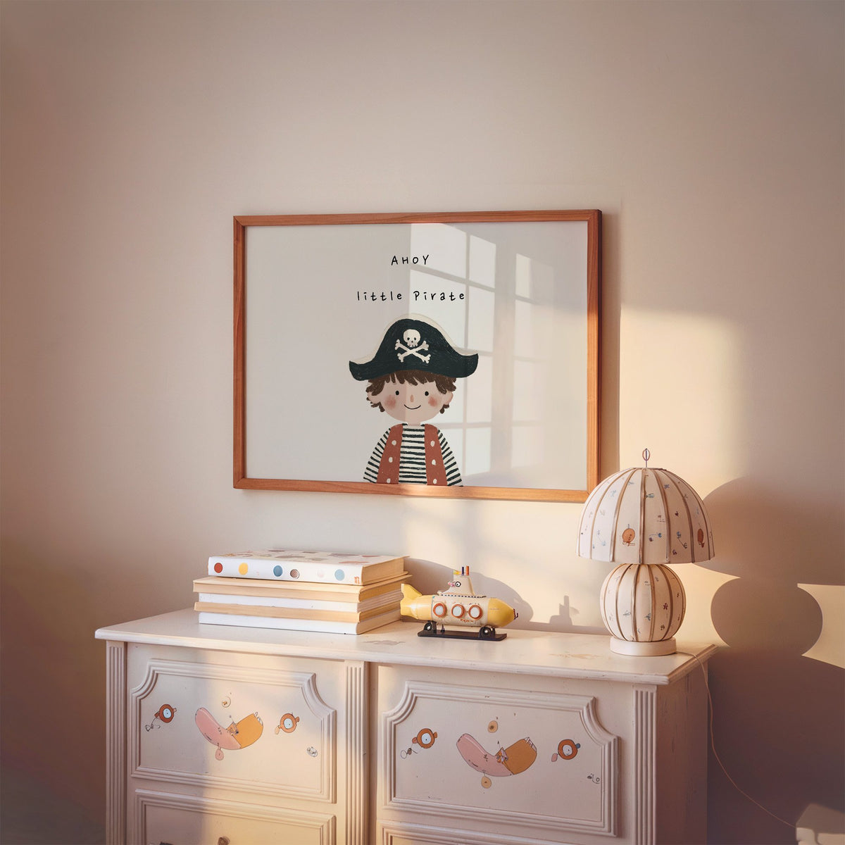 Landscape ahoy little pirate boy nursery print in a cherry wood frame above a painted dresser and lamp