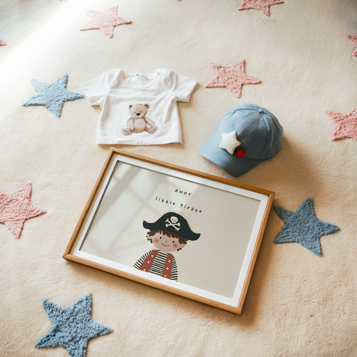 Landscape ahoy little pirate boy nursery print in a matted oak frame on a star rug with a baby tee