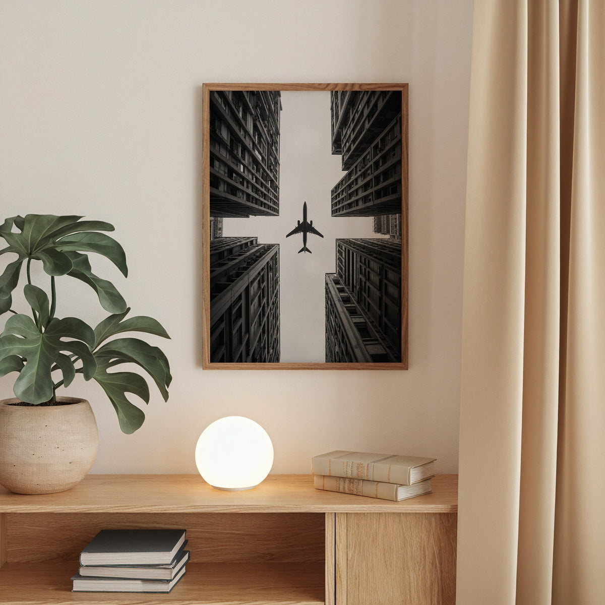 Airplane flying between four skyscrapers print in a walnut frame above an oak cabinet with a glowing globe lamp