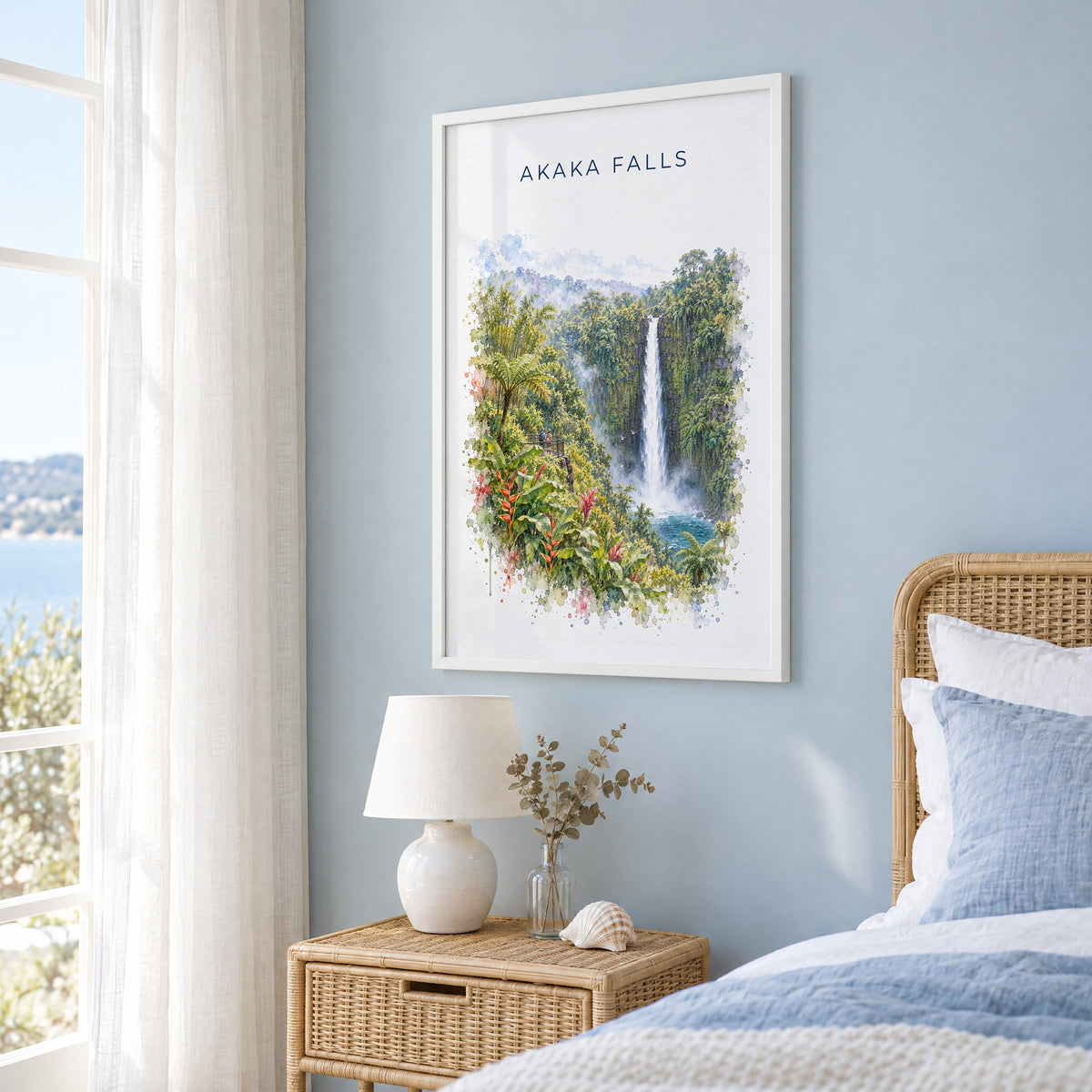 Akaka Falls watercolor print in a white frame on a pale blue wall beside a rattan bed in a coastal bedroom
