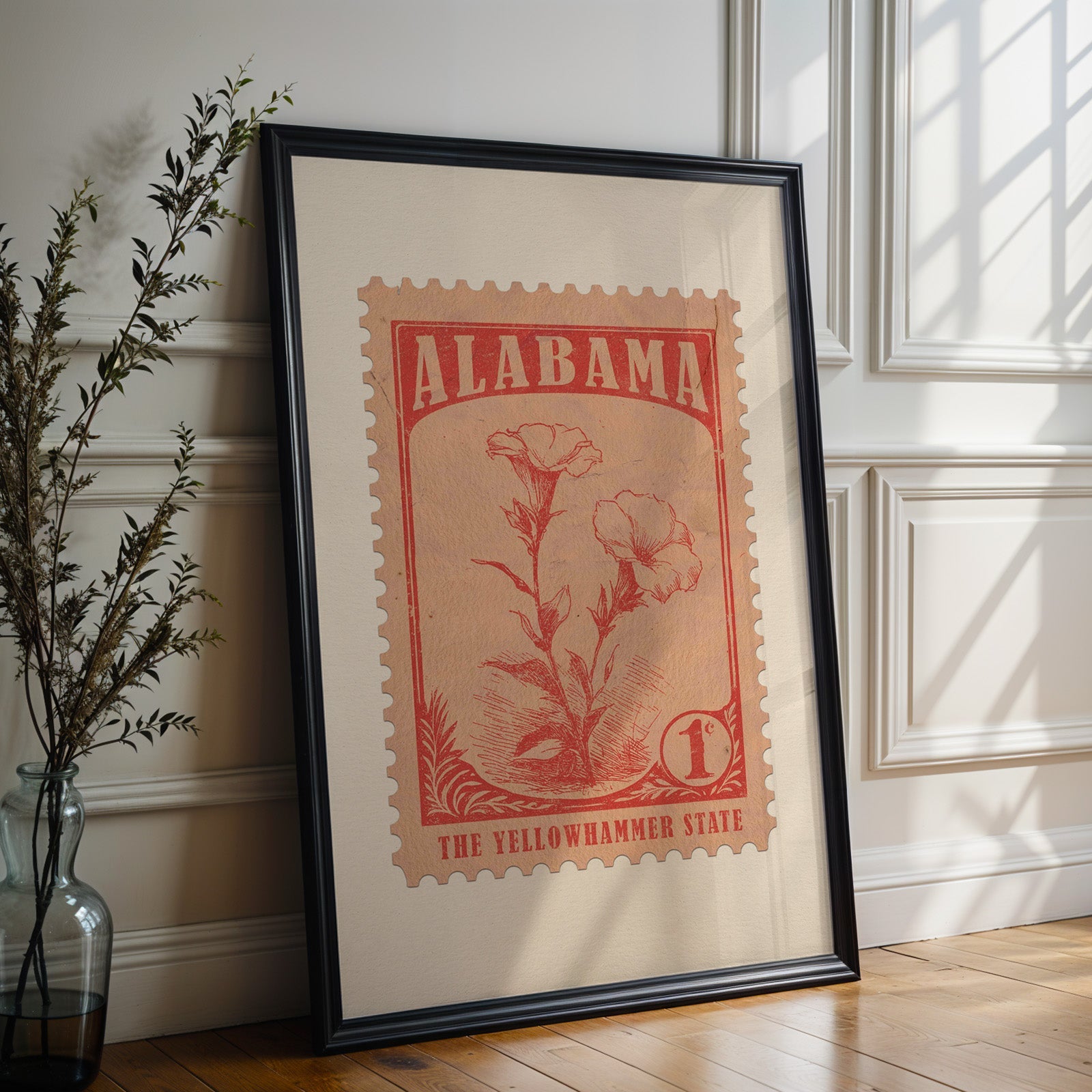 Alabama state flower print in a black frame leaning against a white panelled wall beside olive branches