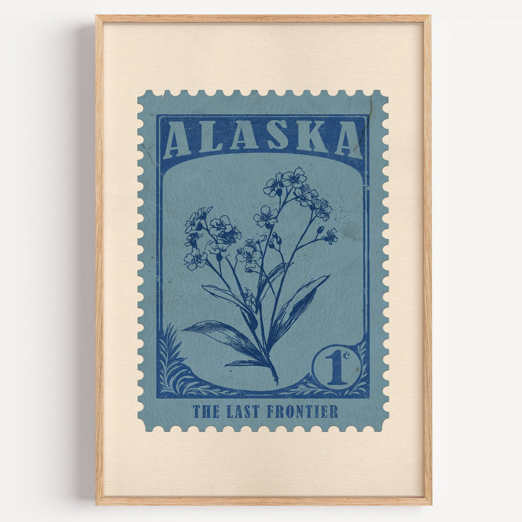 Alaska state flower stamp print in ink blue on dusty sky, light oak frame on a plain white wall