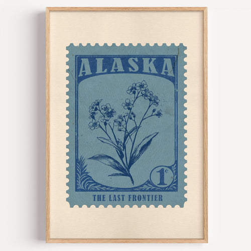 Alaska state flower stamp print in ink blue on dusty sky, light oak frame on a plain white wall