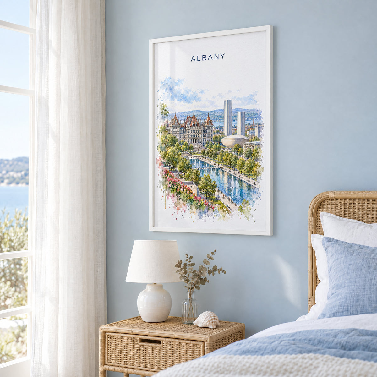Albany, New York watercolor print in a white frame on a pale blue wall beside a rattan bed in a coastal bedroom