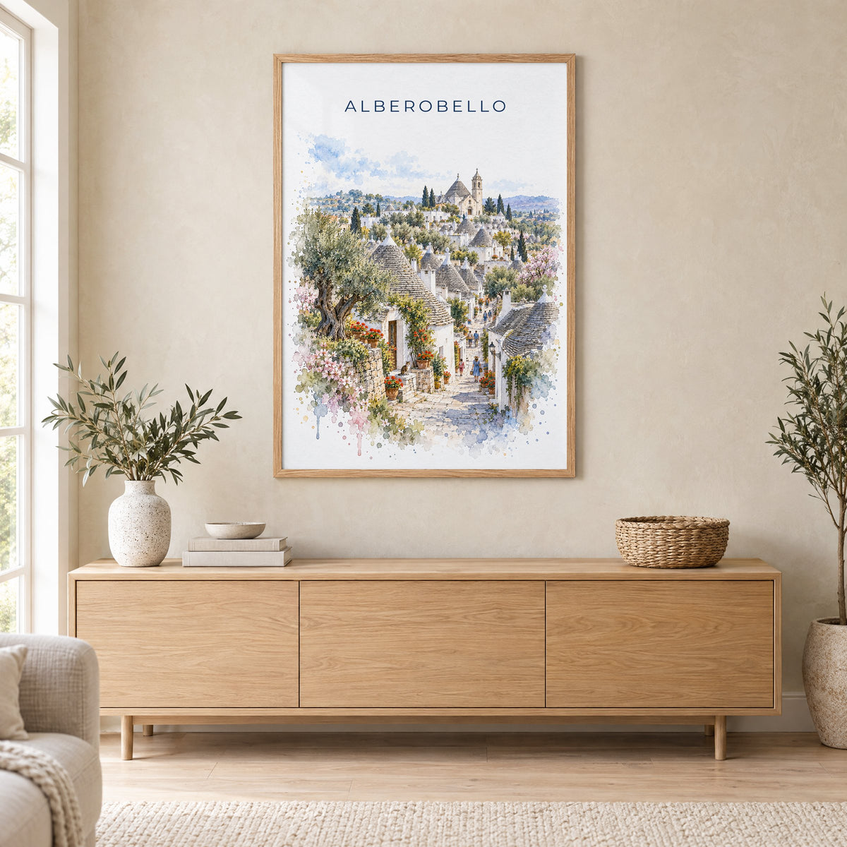 Alberobello watercolor print in an oak frame above a light wood sideboard in a Scandinavian living room