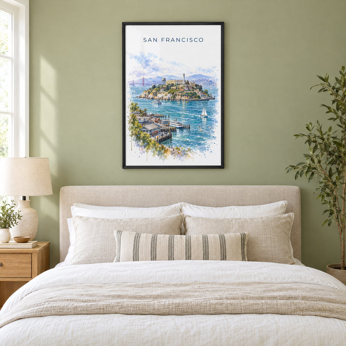 Alcatraz Island watercolor print in a black frame above an upholstered headboard in a sage green bedroom