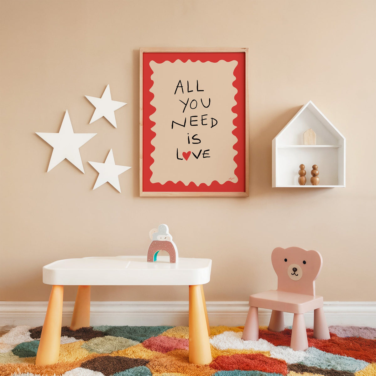 All you need is love heart nursery print in an oak frame on a peach wall above a kids table with wall stars