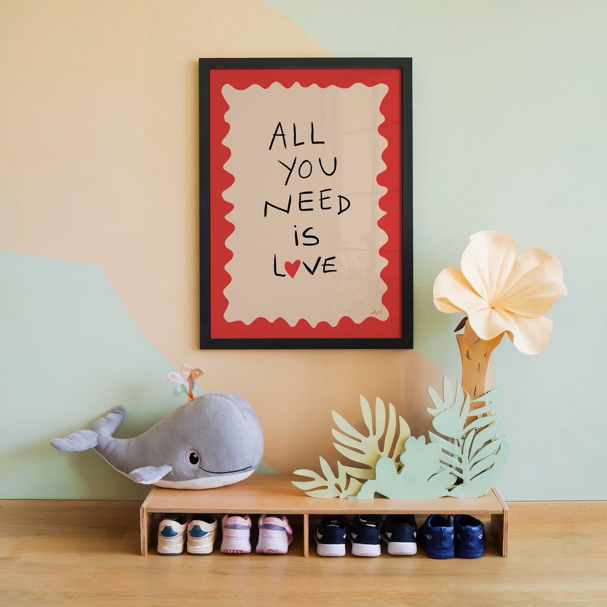 All you need is love heart nursery print in a black frame on a mint and peach wall above a whale plush