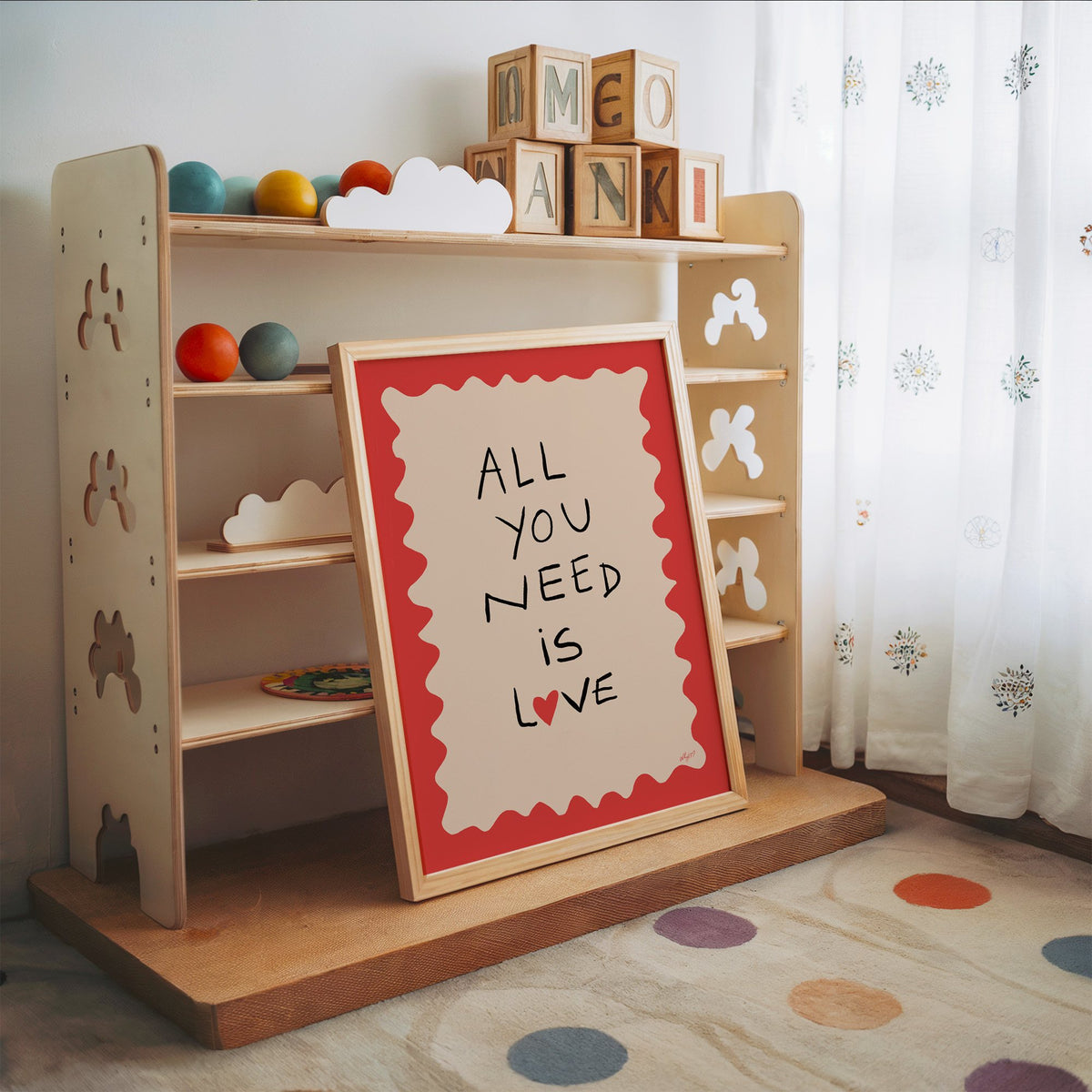 All you need is love heart nursery print in an oak frame leaning on a toy shelf with wooden letter blocks