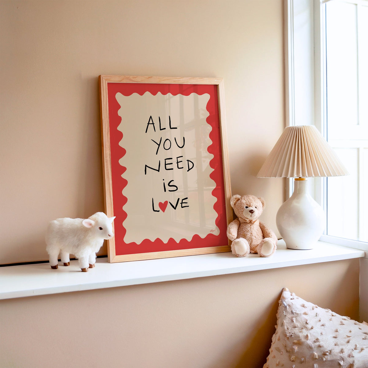 All you need is love heart nursery print in an oak frame on a window ledge with a toy lamb and teddy