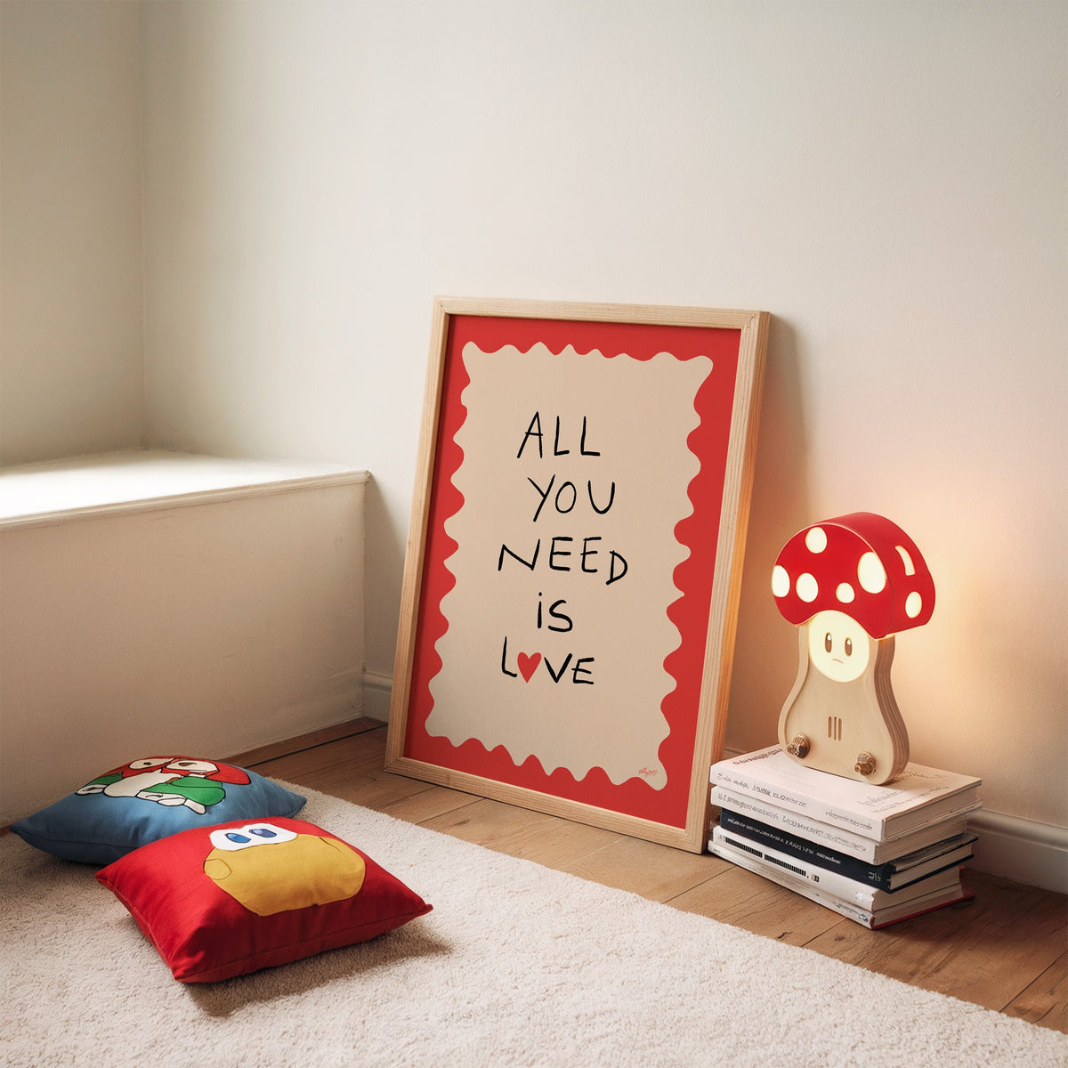 All you need is love heart nursery print in an oak frame leaning on a rug beside a mushroom lamp and floor cushions