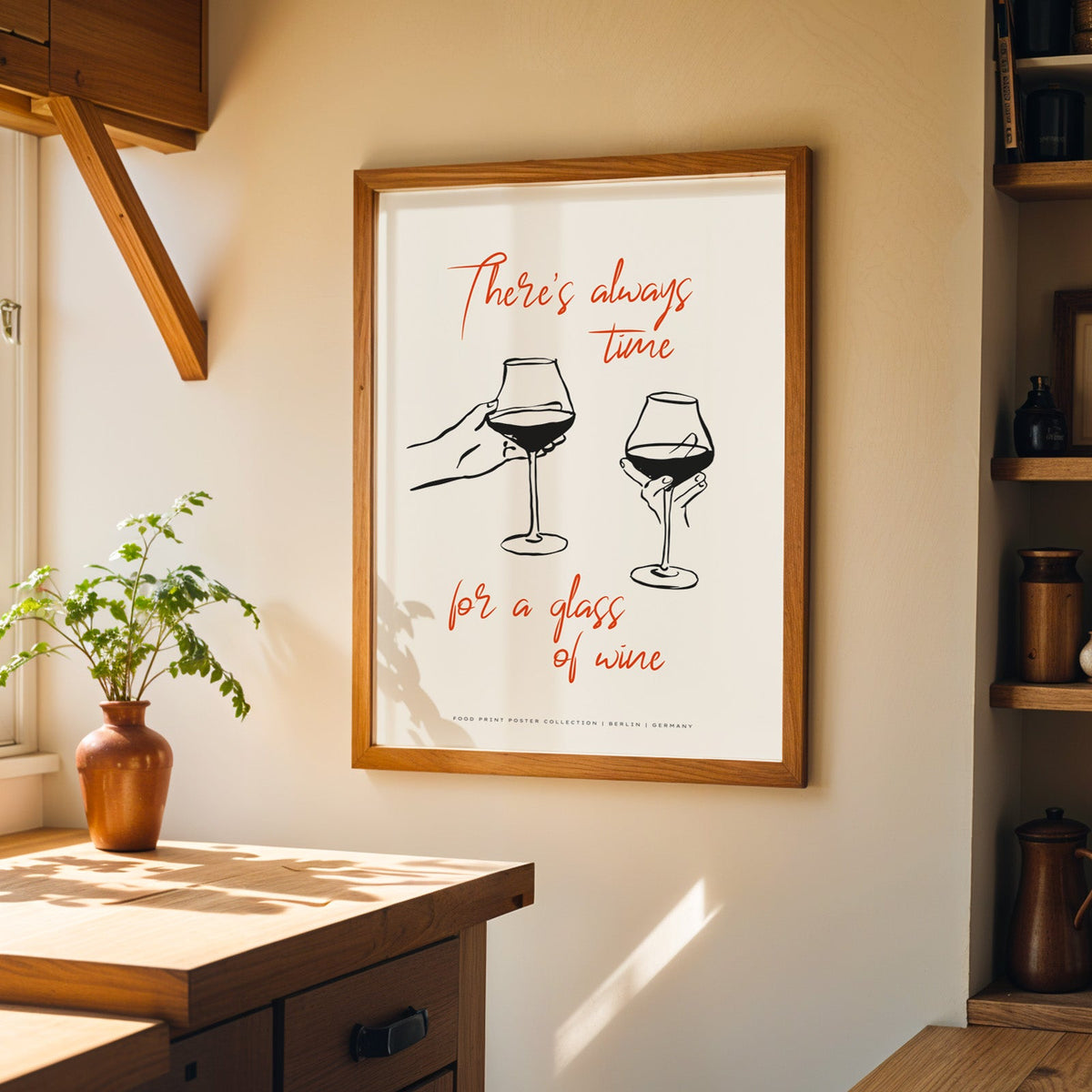 Wine quote print in a wood frame on a sunlit kitchen wall beside open shelving