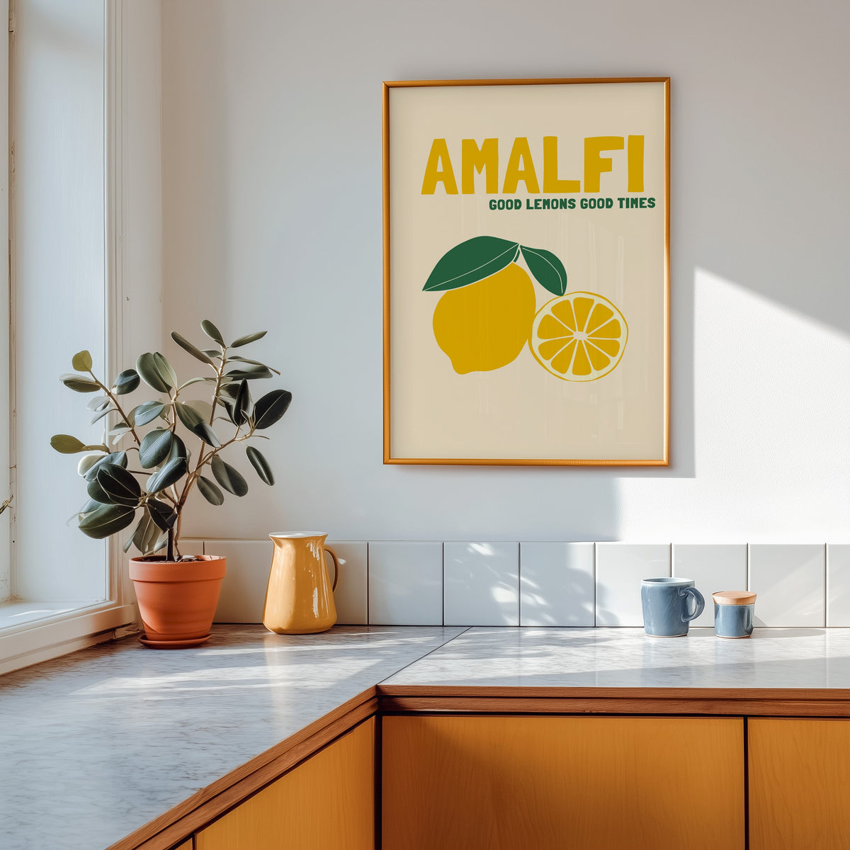 Amalfi lemon print shown in a gold frame above a marble counter in a tan kitchen