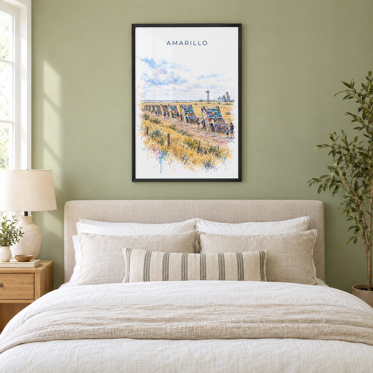 Amarillo watercolor print in a black frame above an upholstered headboard in a sage green bedroom