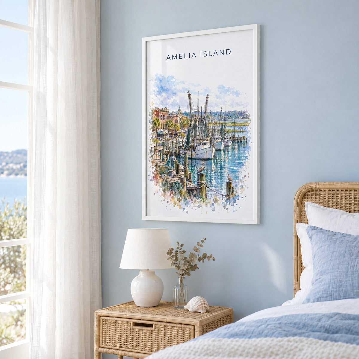 Amelia Island watercolor print in a white frame on a pale blue wall beside a rattan bed in a coastal bedroom