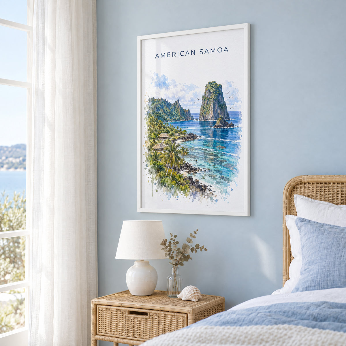 American Samoa National Park watercolor print in a white frame on a pale blue wall beside a rattan bed in a coastal bedroom
