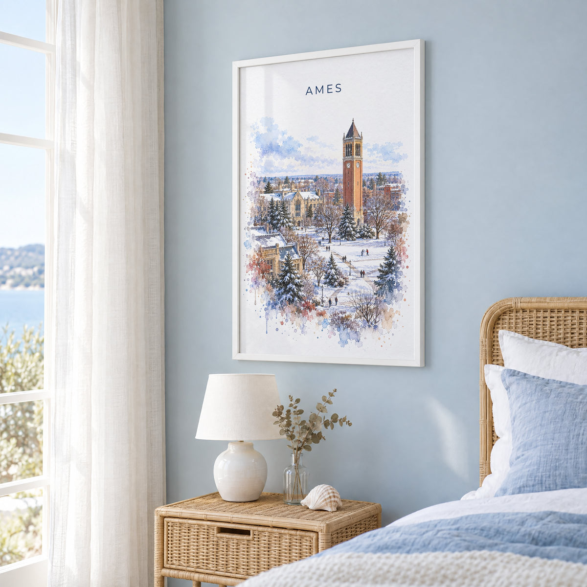 Ames, Iowa watercolor print in a white frame on a pale blue wall beside a rattan bed in a coastal bedroom