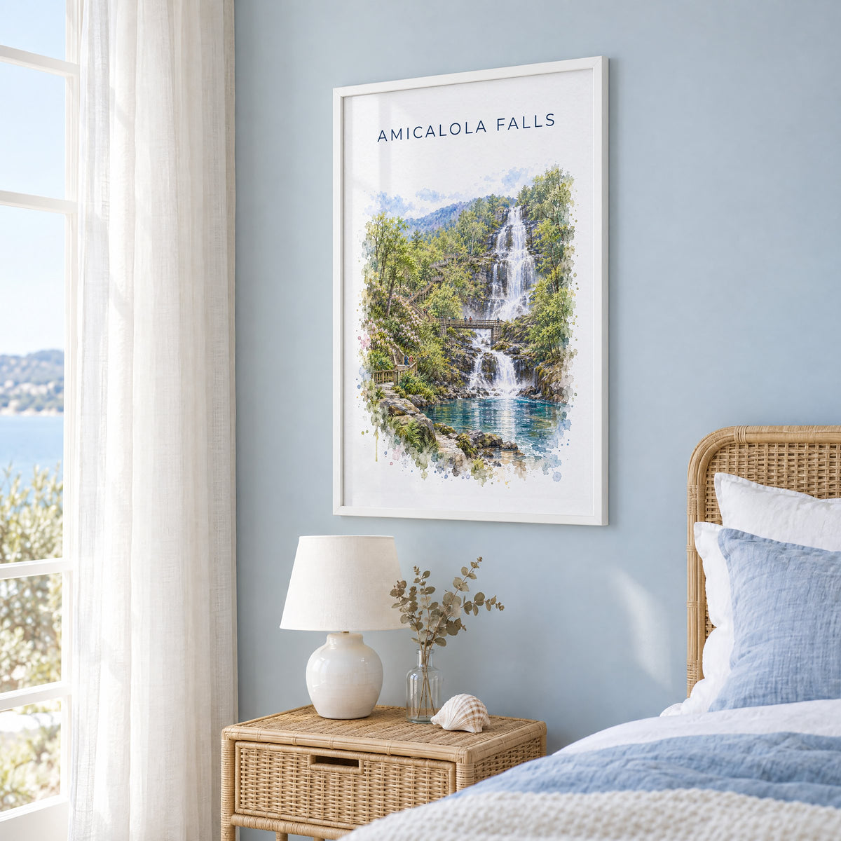 Amicalola Falls State Park watercolor print in a white frame on a pale blue wall beside a rattan bed in a coastal bedroom