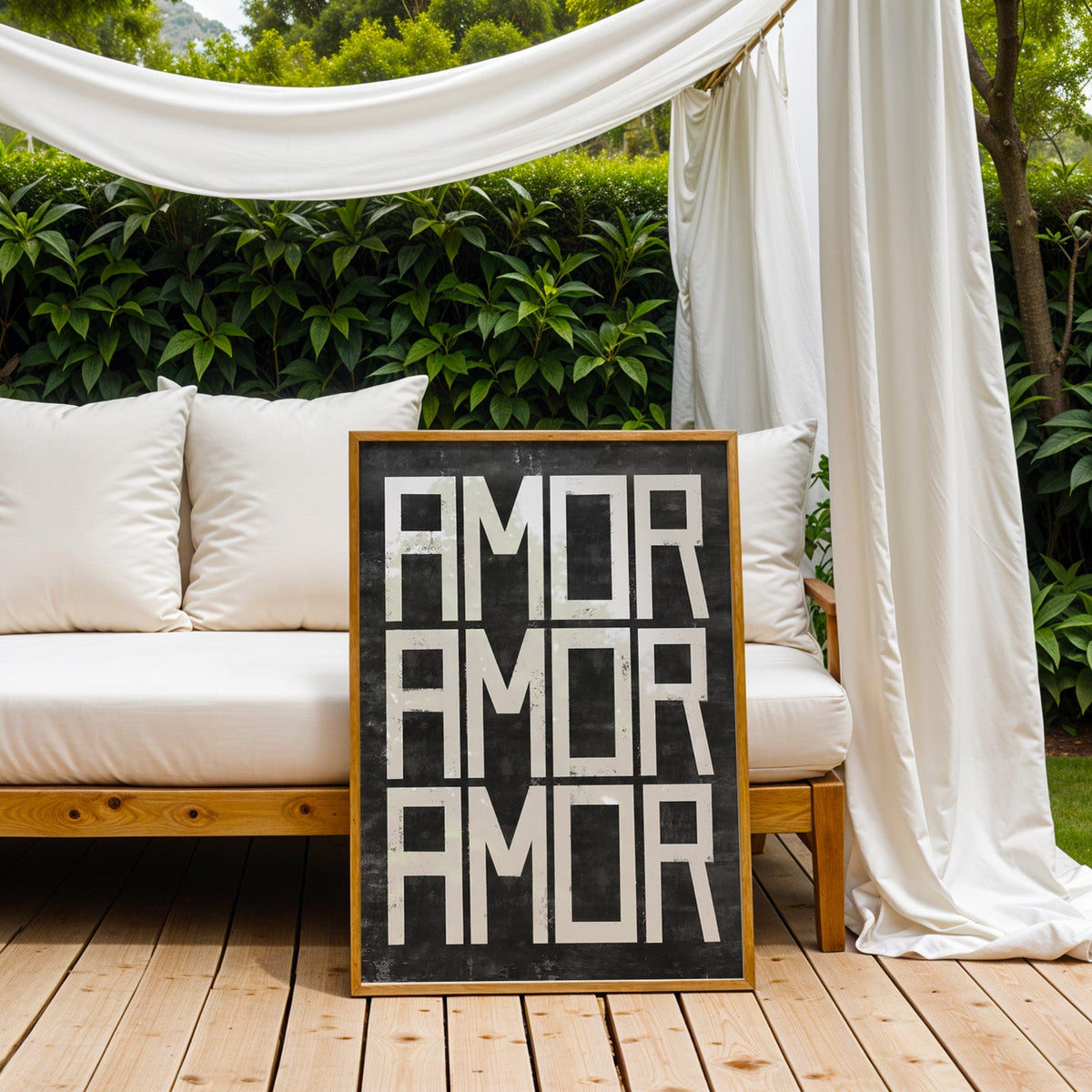 Amor three times white distressed lettering print in an oak frame on an outdoor daybed under white drapes