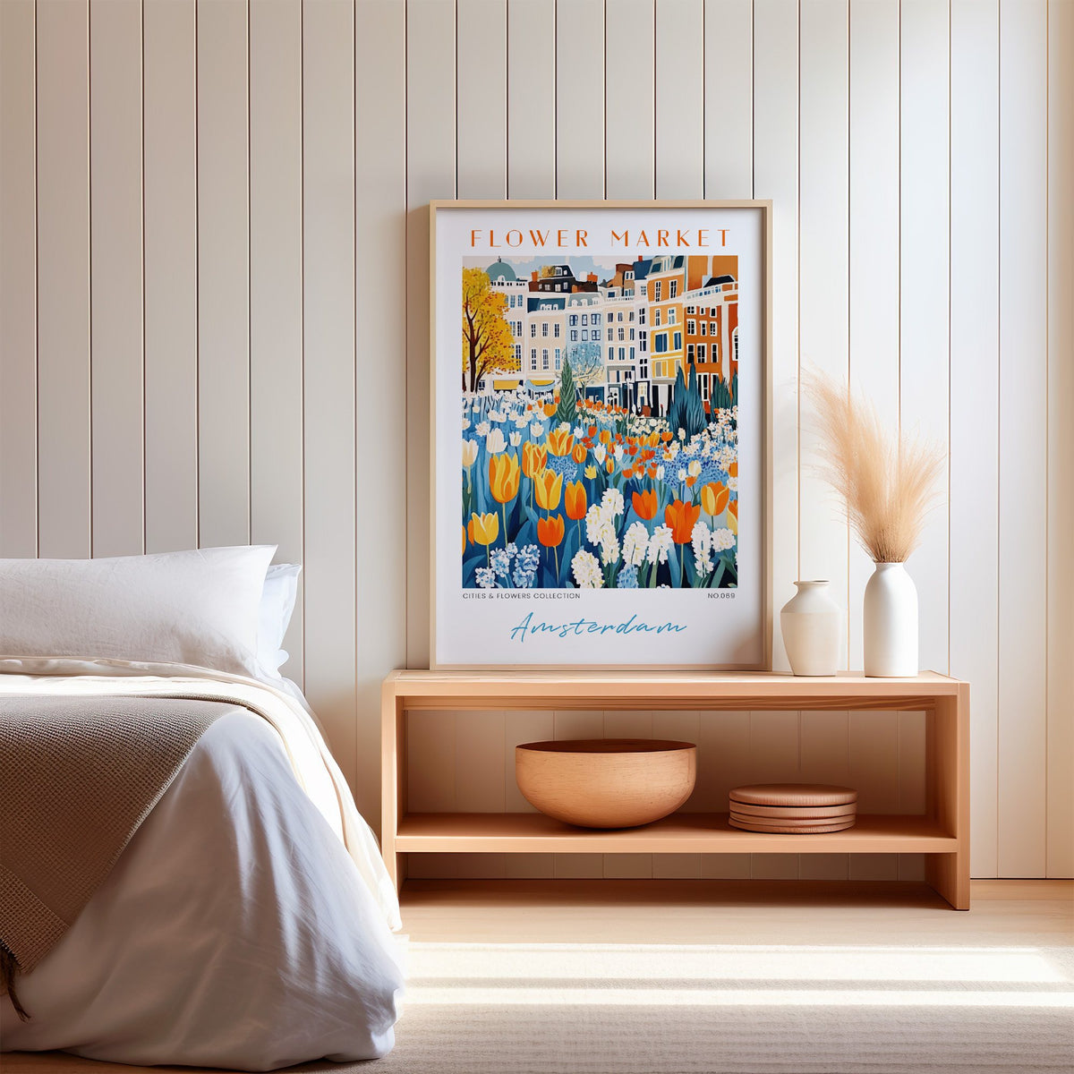 Amsterdam flower market print in an oak frame on a wood bench against a white shiplap bedroom wall with pampas grass