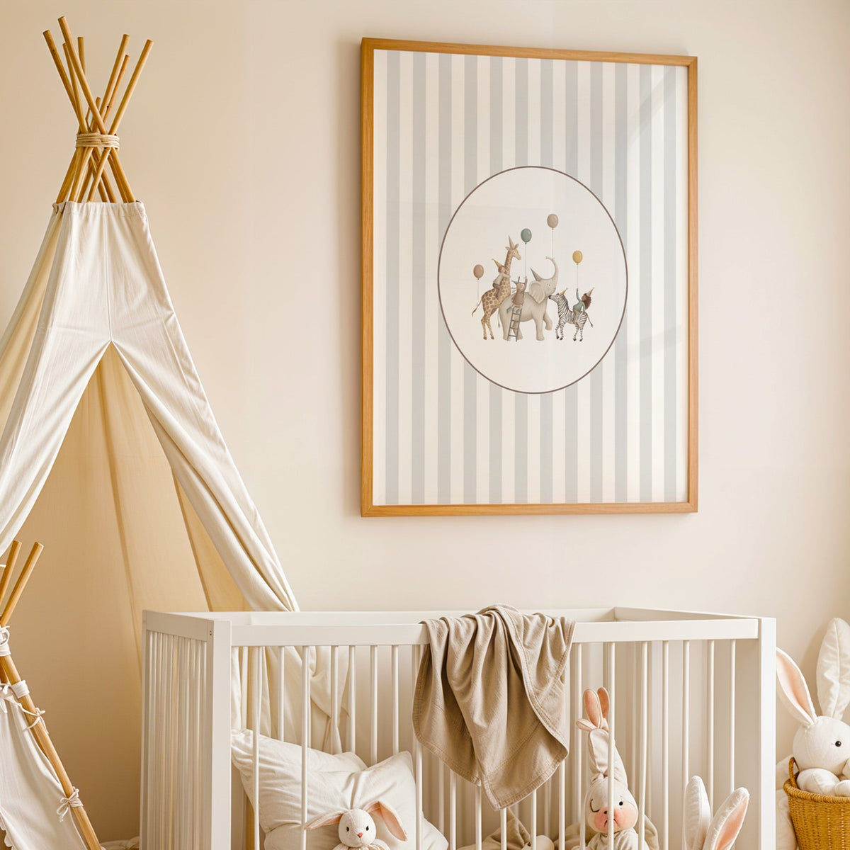 Animal birthday parade in an oval on stripes nursery print in an oak frame above a white crib beside a canvas teepee