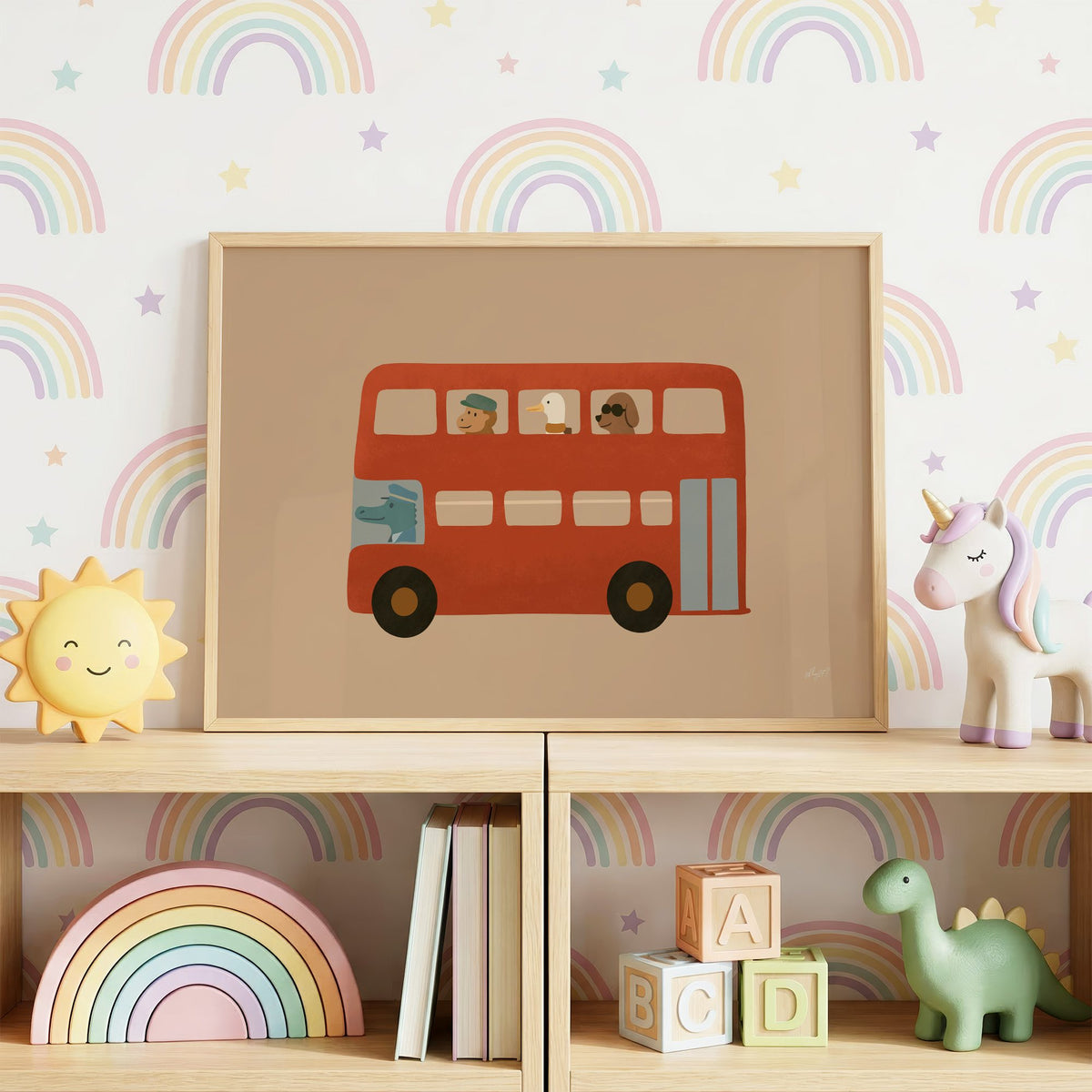 Animals riding red double decker bus nursery print in an oak frame on a toy shelf against rainbow wallpaper
