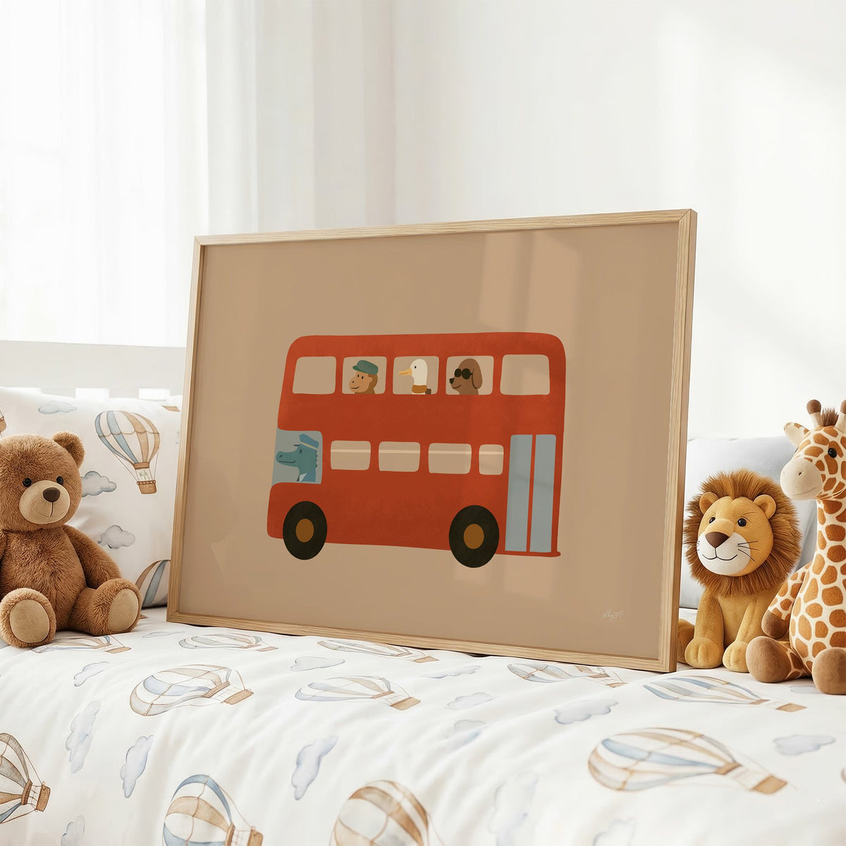 Animals riding red double decker bus nursery print in an oak frame on a kids bed with hot air balloon bedding