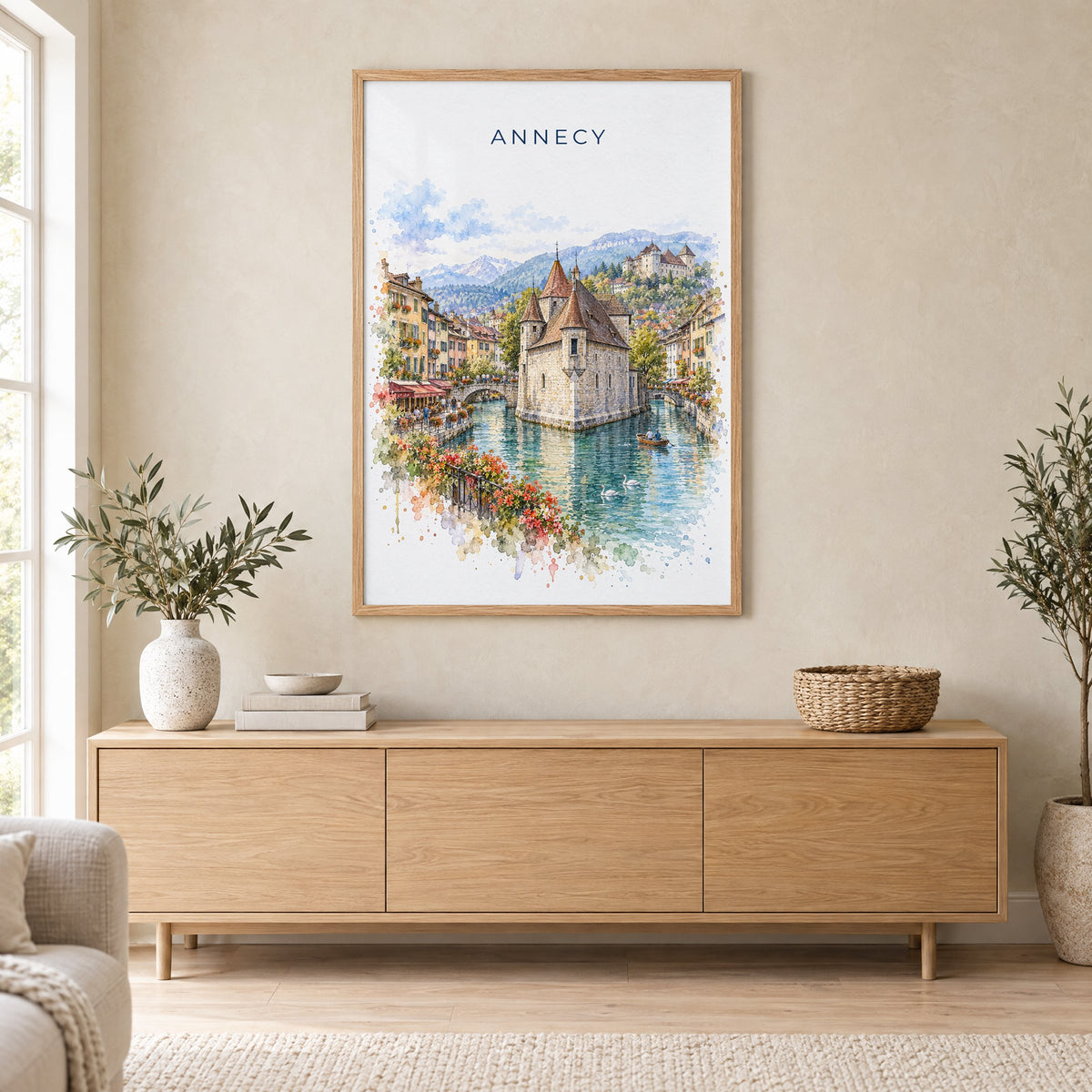 Annecy watercolor print in an oak frame above a light wood sideboard in a Scandinavian living room