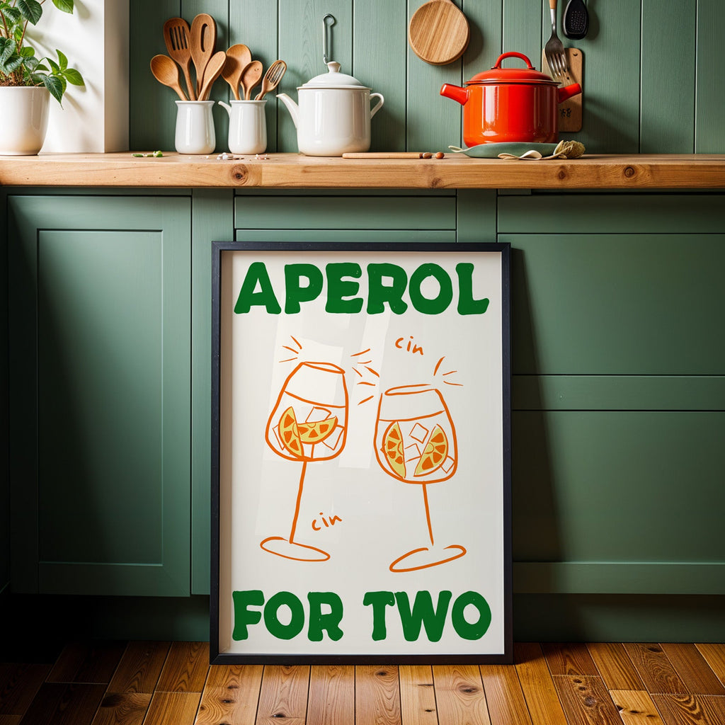 Aperol spritz print in a black frame against sage green kitchen cabinets