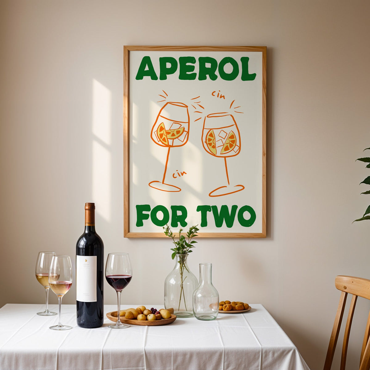 Aperol spritz print in an oak frame above a table laid with red wine and glasses