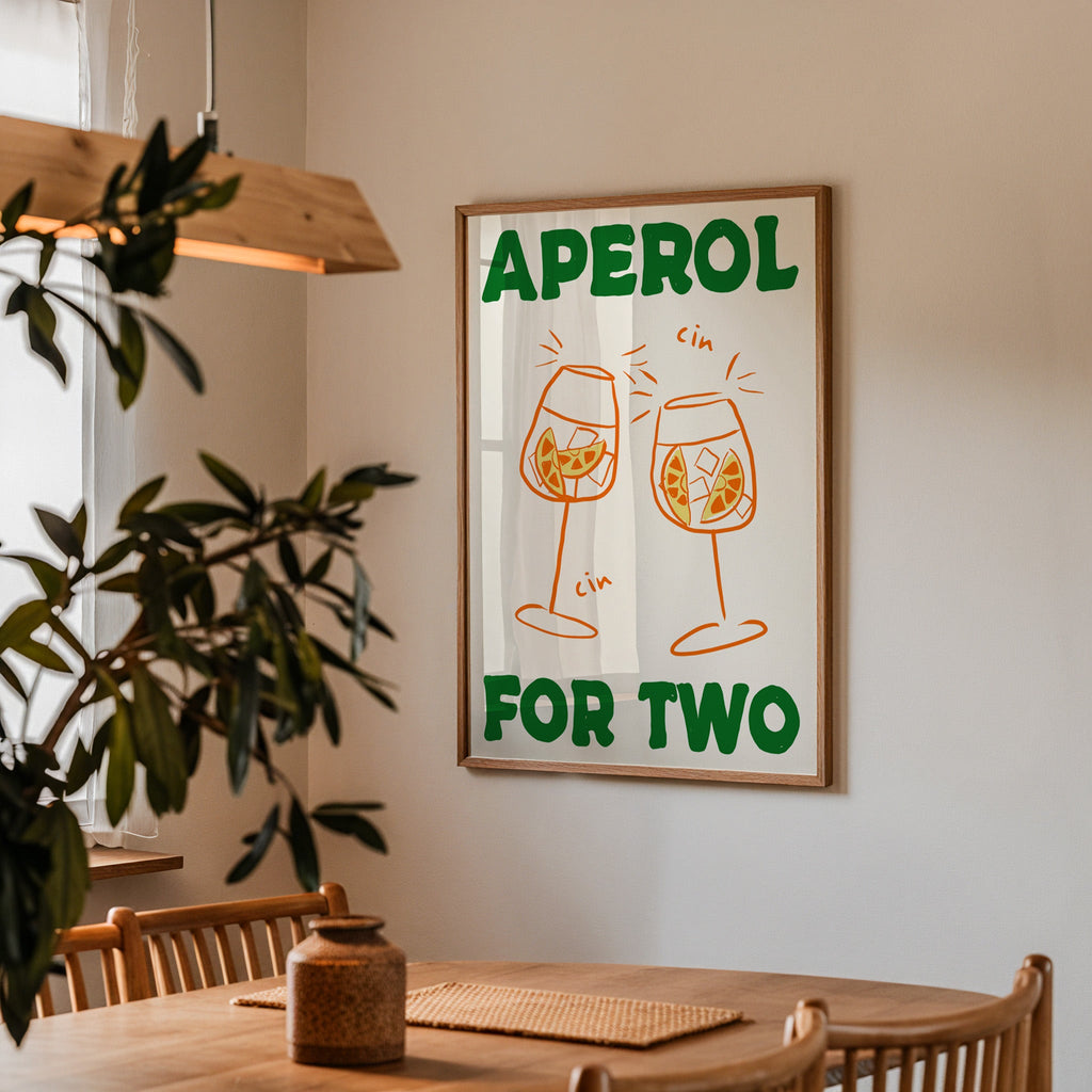 Aperol spritz print in a walnut frame above a dining table beside an olive tree