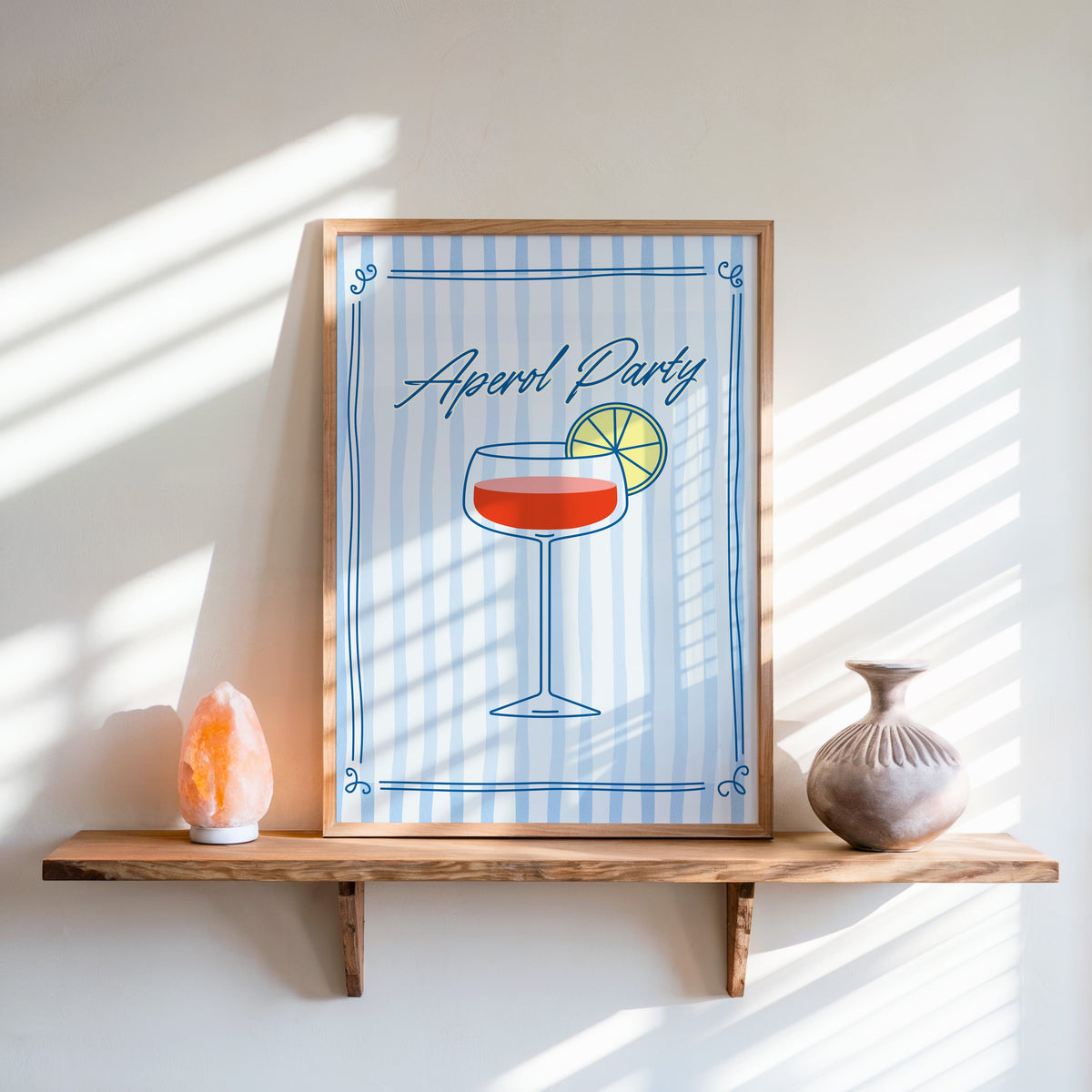 Aperol Party print in an oak frame on a live-edge shelf beside a salt lamp