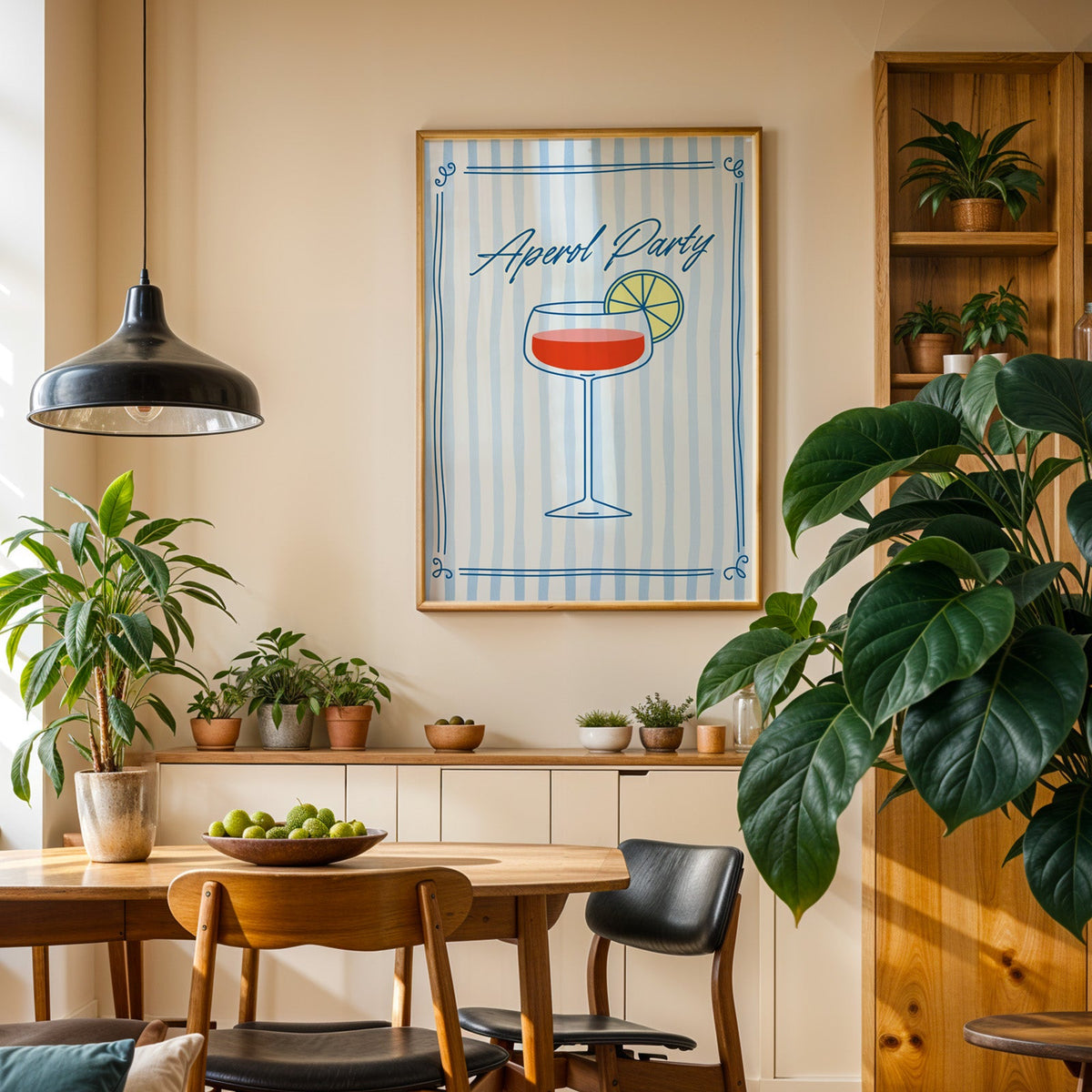 Aperol Party print in an oak frame in a dining room above a plant-lined sideboard