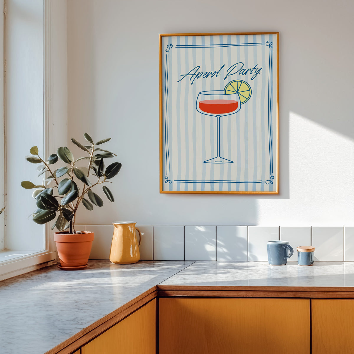 Aperol Party print shown in a gold frame above a marble counter in a tan kitchen