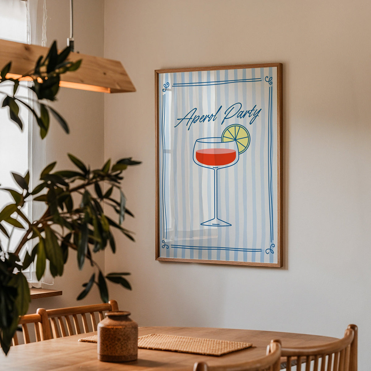 Aperol Party print in a walnut frame above a dining table with olive branches