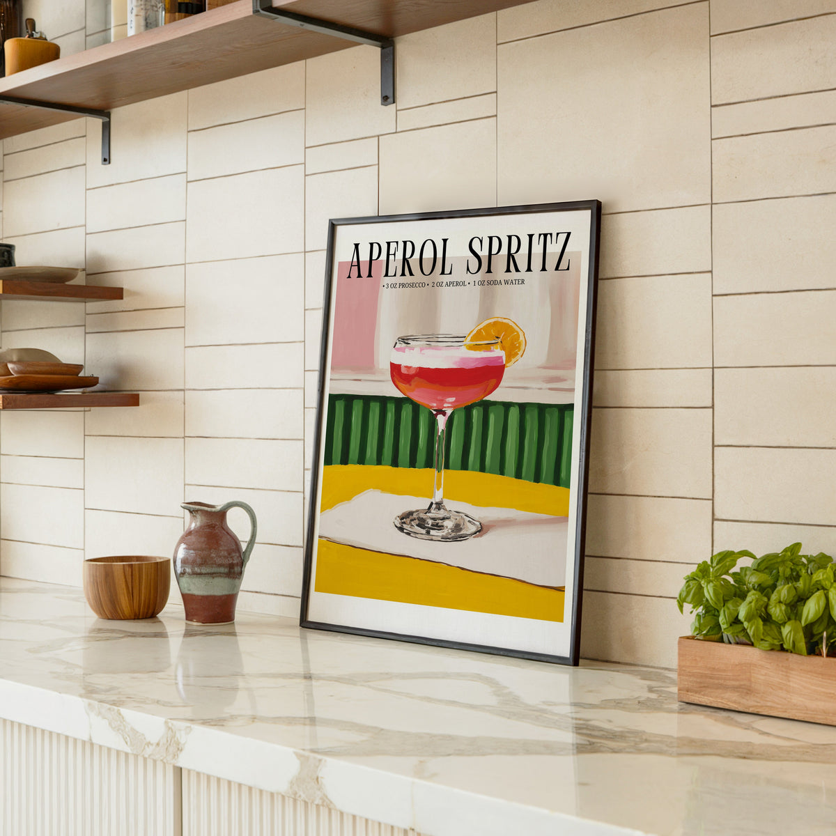 Aperol Spritz recipe print in a black frame leaning on a marble counter in a tiled kitchen