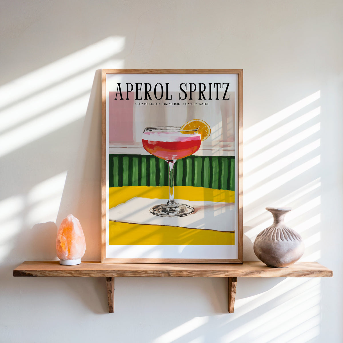 Aperol Spritz recipe print in an oak frame on a live-edge shelf beside a salt lamp