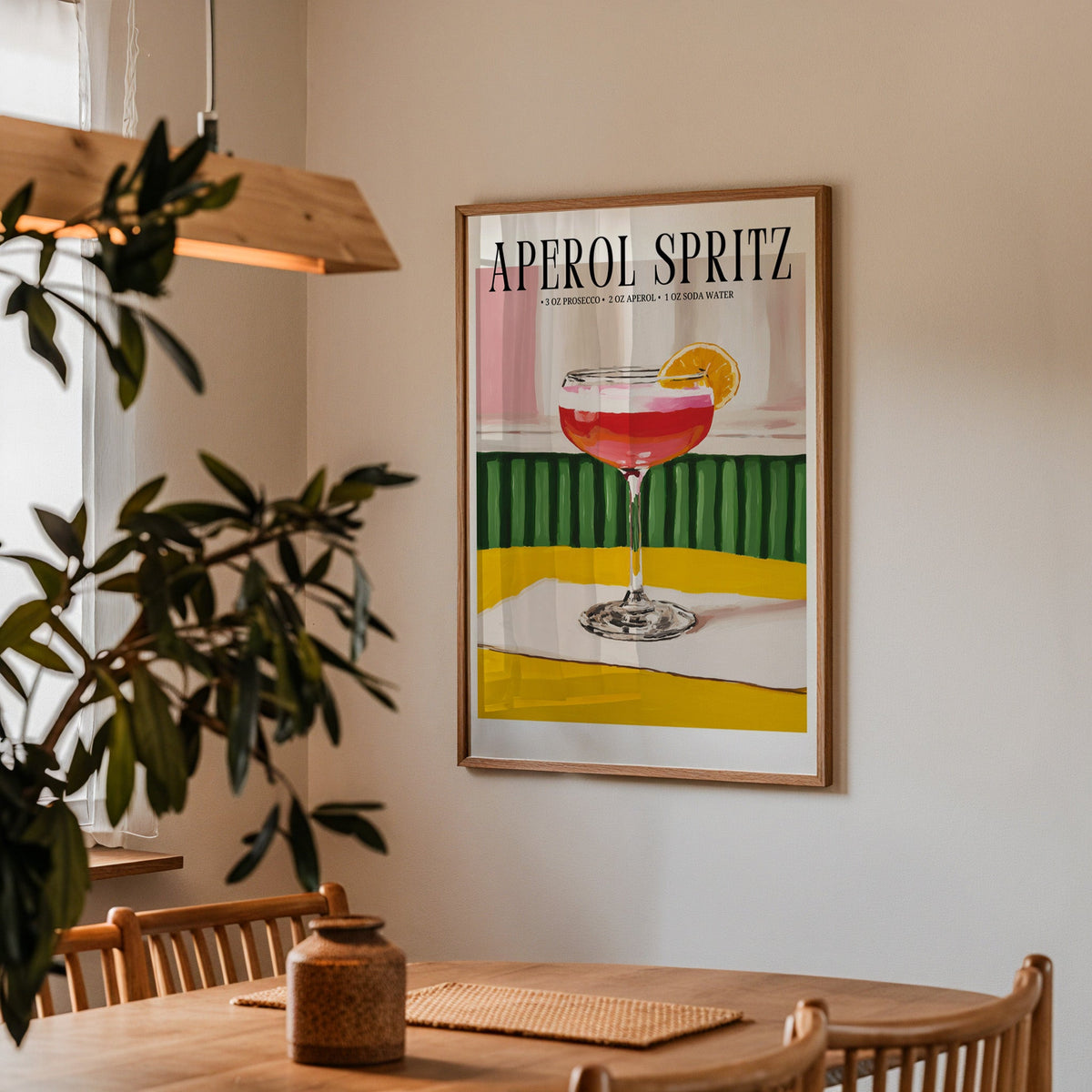 Aperol Spritz recipe print in a walnut frame above a dining table with olive branches