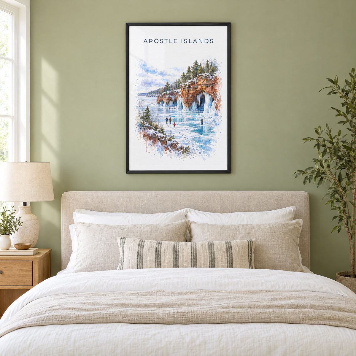 Apostle Islands watercolor print in a black frame above an upholstered headboard in a sage green bedroom