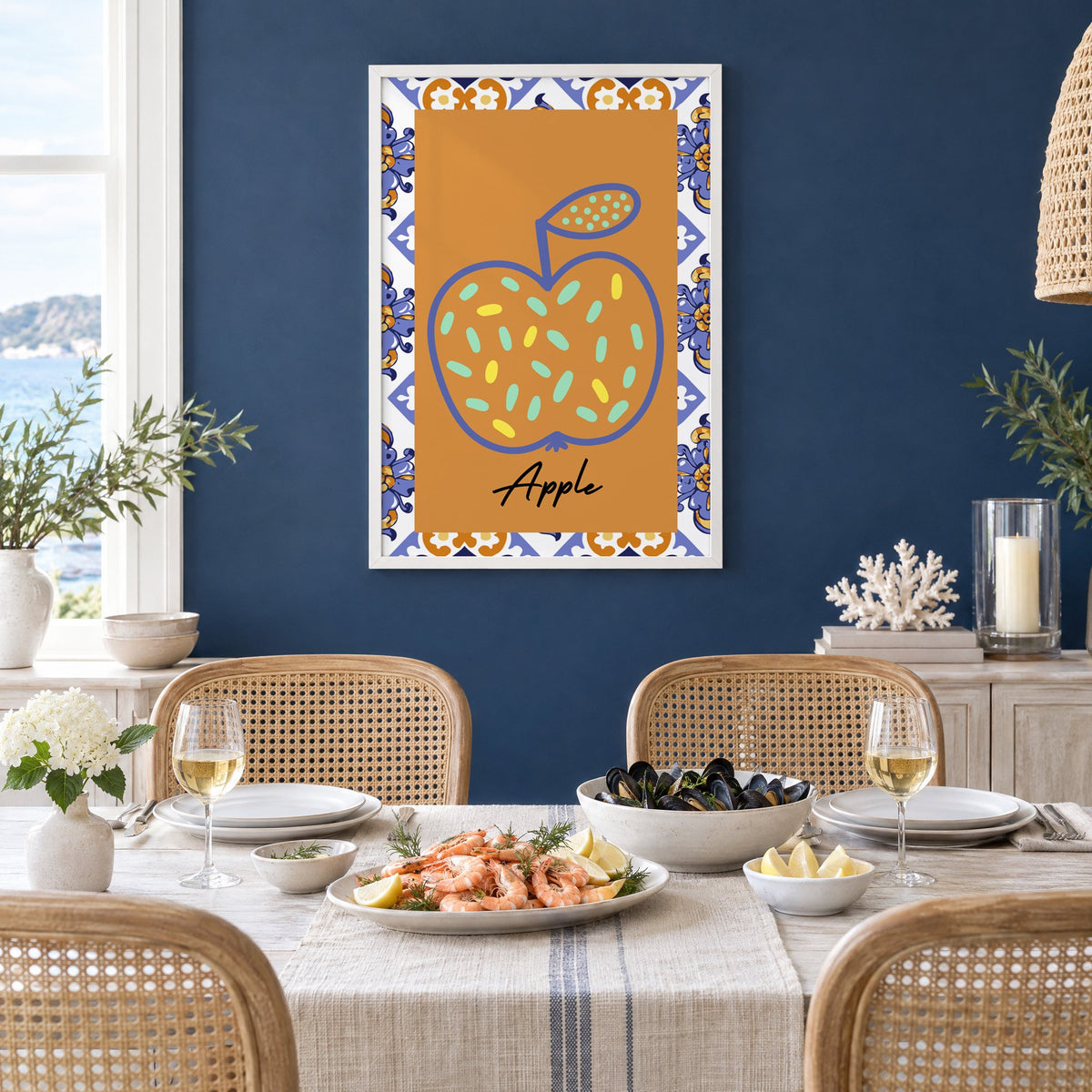 Apple blue outline ochre majolica print in a white frame on a navy wall above a dining table set with shrimp and mussels