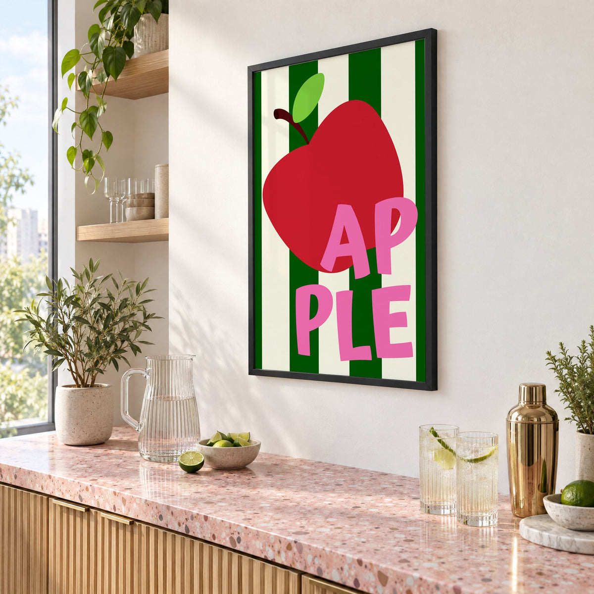 AP PLE red apple stripes print in a black frame above a pink terrazzo cocktail counter with limes, seen at an angle