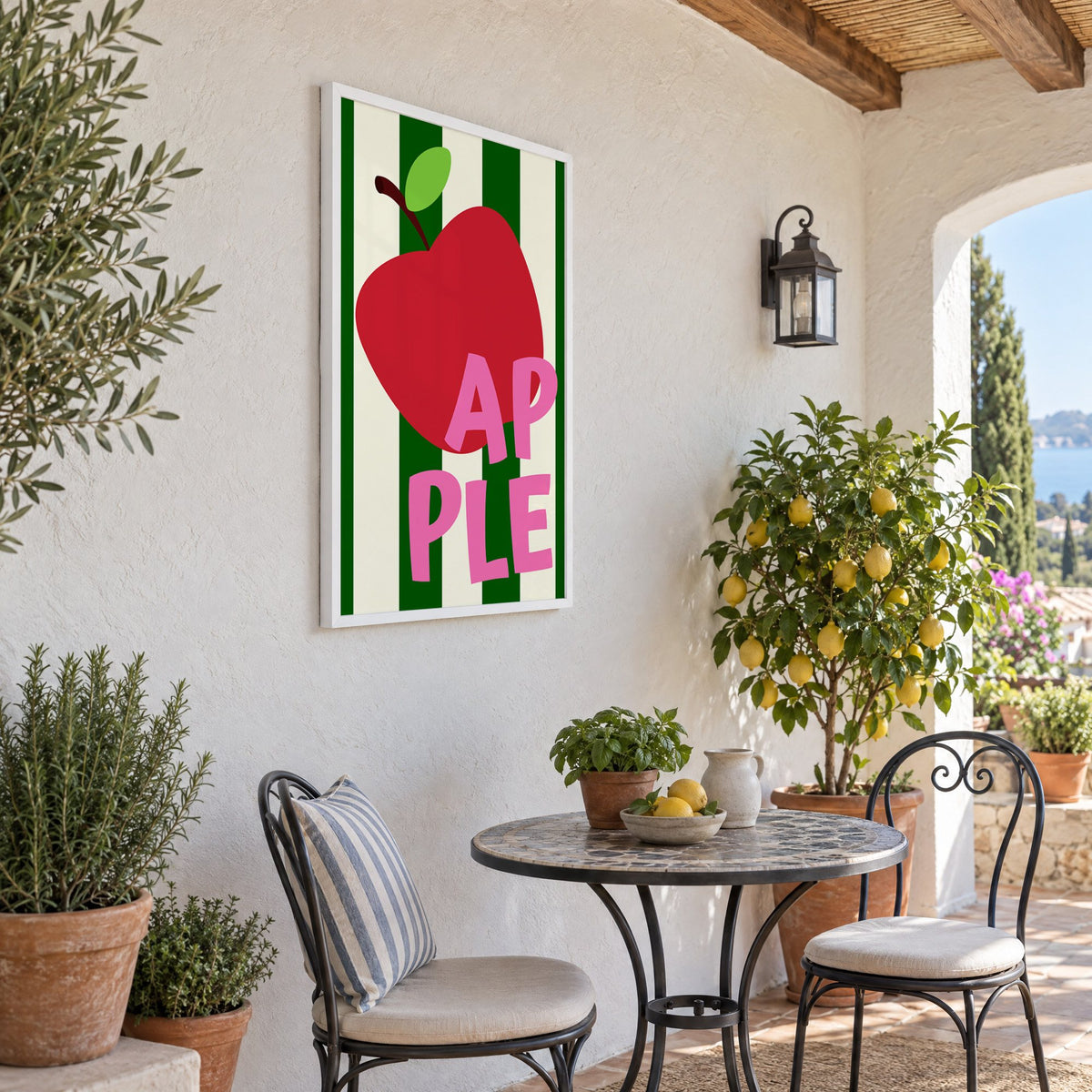 AP PLE red apple stripes print in a white frame on a sunny patio wall beside a potted lemon tree